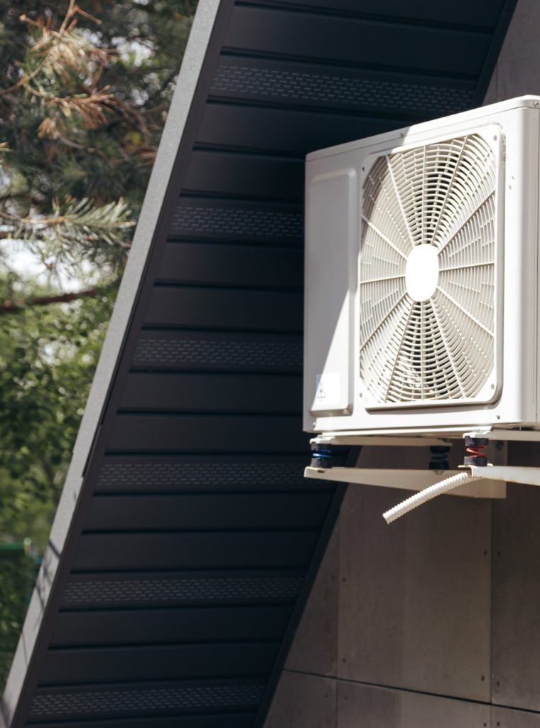 External unit of an air conditioner on facade of small wooden forest house