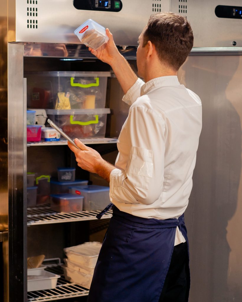 professional kitchen chef looks into fridge and chooses ingredients for cooking food concept